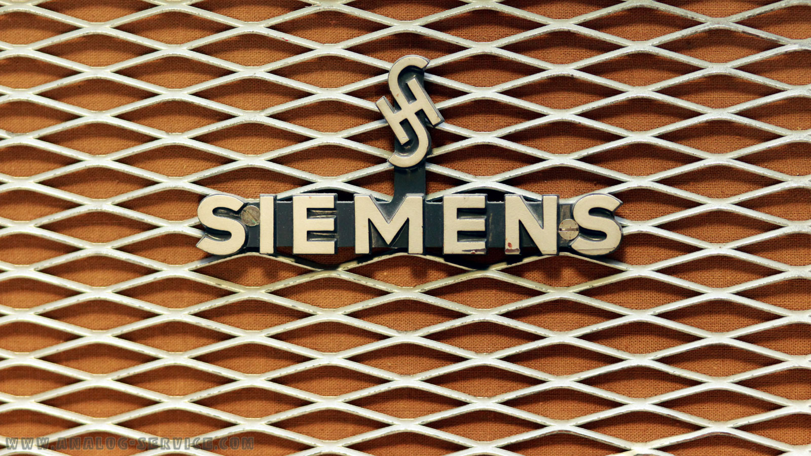 Das Logo in Großaufnahme. Es wurde das Siemens & Halske Logo (H über S) verwendet. Darunter steht Siemens. Das logo ist sehr groß und massiv ausgeführt